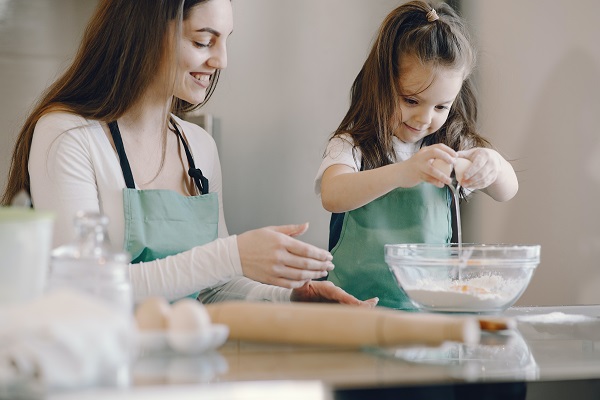 best baking appliances in the kitchen with mum and daughter baking together in kitchen with flour on table wearing aprons